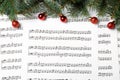 Fir tree branches and red balls on Christmas music sheets with notes, flat lay Royalty Free Stock Photo