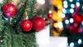 Fir tree branches with red new year balls on a background of colorful beautiful bokeh, close-up. Concept of Christmas composition Royalty Free Stock Photo