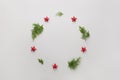 Fir tree branches and red stars shaped as wreath frame on white background, Merry Christmas and Happy Hew composition Royalty Free Stock Photo