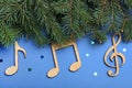Fir tree branches with wooden music notes on blue background, flat lay. Christmas celebration Royalty Free Stock Photo