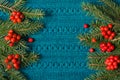 Fir tree and red berries of viburnum as frame on knitted sweater background. Christmas concept. Flat lay. Royalty Free Stock Photo