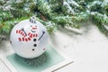 Fir tree toy ball decorated with joyful snowman on Christmas card next to fir tree branches on white textured background Royalty Free Stock Photo