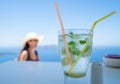 Frosty glass with mojito drink in focus in foreground with person in background out of focus