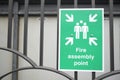 Fire assembly point sign at workplace car park fence Royalty Free Stock Photo