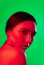 Beautiful east woman close up portrait isolated on green background in red neon light Royalty Free Stock Photo