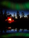 Fire burning at night in a forest with northern lights Royalty Free Stock Photo