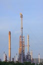 Fire burning over oil refinery chimney against blue sky