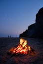 Fire burning on the sand coast on a sunny summer evening. Small fire burns inside a fireplace on the empty beach at Royalty Free Stock Photo