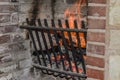 Fire burns in a brick fireplace with a metal grate Royalty Free Stock Photo