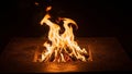 Burns in a square metal fire pit with flames rising and casting a Royalty Free Stock Photo