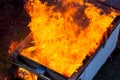 Fire coils over a burnt building. A pile of coals at the site of a burnt shed. Bright flames, flying ashes of a burning wooden Royalty Free Stock Photo