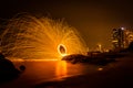 Fire dancer swing fire dancing show on the beach with dark clouds, twilight sky background. Royalty Free Stock Photo