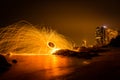 Fire dancer swing fire dancing show on the beach with dark clouds, twilight sky background. Royalty Free Stock Photo