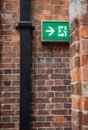 Fire emergency exit sign on a brown old brick wall. Royalty Free Stock Photo