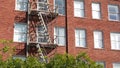 Fire escape ladder outside residential brick building in San Diego city, USA. Typical New York style emergency exit for safe Royalty Free Stock Photo