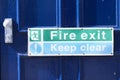 Fire exit keep clear sign on building blue exit door Royalty Free Stock Photo