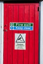 Fire Exit And Keep Clear Sign On A Red Painted Wooden Door With No People