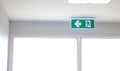Fire Exit sign on the ceiling entry the fire escape, green safety light symbol isolated in white window. Caution for warning.