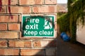 Fire Exit sign seen outside a business entrance, seen down a very narrow street.