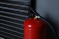 Fire extinguisher near grey wall indoors, closeup. Space for text Royalty Free Stock Photo