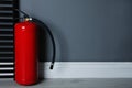 Fire extinguisher near grey wall. Space for text Royalty Free Stock Photo