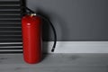 Fire extinguisher near grey wall. Space for text Royalty Free Stock Photo