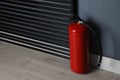 Fire extinguisher near grey wall. Space for text Royalty Free Stock Photo