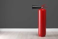 Fire extinguisher near grey wall, space for text Royalty Free Stock Photo