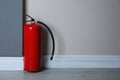 Fire extinguisher near light wall. Space for text Royalty Free Stock Photo