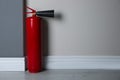 Fire extinguisher near wall indoors. Space for text Royalty Free Stock Photo