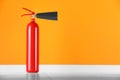 Fire extinguisher near orange wall, space for text Royalty Free Stock Photo