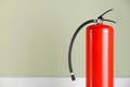 Fire extinguisher near pale green wall, space for text Royalty Free Stock Photo