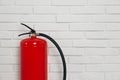 Fire extinguisher near white brick wall. Space for text Royalty Free Stock Photo