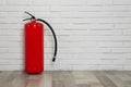 Fire extinguisher near white brick wall, space for text Royalty Free Stock Photo