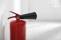 Fire extinguisher near white wall indoors. Space for text Royalty Free Stock Photo