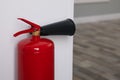 Fire extinguisher near white wall, closeup. Space for text Royalty Free Stock Photo