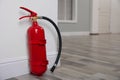 Fire extinguisher near white wall. Space for text Royalty Free Stock Photo