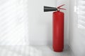 Fire extinguisher near white wall indoors. Royalty Free Stock Photo