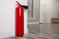Fire extinguisher near white wall indoors. Space for text Royalty Free Stock Photo