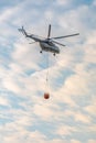 A fire fighter helicopter with a full basket of water flies against a beautiful sky Royalty Free Stock Photo