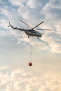 A fire fighter helicopter with a full basket of water flies against a beautiful sky Royalty Free Stock Photo