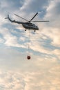 A fire fighter helicopter with a full basket of water flies against a beautiful sky Royalty Free Stock Photo