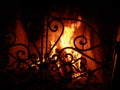 Fire in the fireplace behind a beautiful wrought iron grate with curls. A fire is burning in the fireplace. Night and Royalty Free Stock Photo