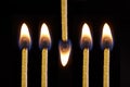 Fire and flame burning on matches sticks as light in the dark against black studio background. Closeup detail of a row Royalty Free Stock Photo