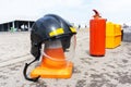 A fire helmet hangs on a traffic cone between a fire extinguisher and a first aid kit. City emergency