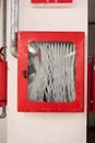 Fire hose mounted on factory wall in closed emergency break red box