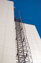 Fire metal staircase on a building tiled wall against a blue sky. vertical view Royalty Free Stock Photo