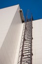 Fire metal staircase on a building tiled wall against a blue sky. vertical view Royalty Free Stock Photo