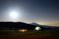 Fire at night, lighting tent and Etna Volcano under moon light