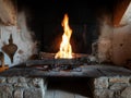 Fire in an open ancient fireplace in a wooden antique stone house Royalty Free Stock Photo